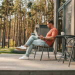 Man som sitter utanför sitt fritidshus och läser